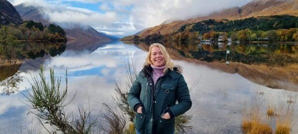 Women standing by loch with mountains